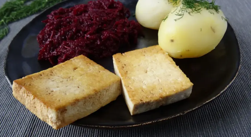 Złociste kotlety z tofu, ziemniaki z koperkiem i buraczki na talerzu.