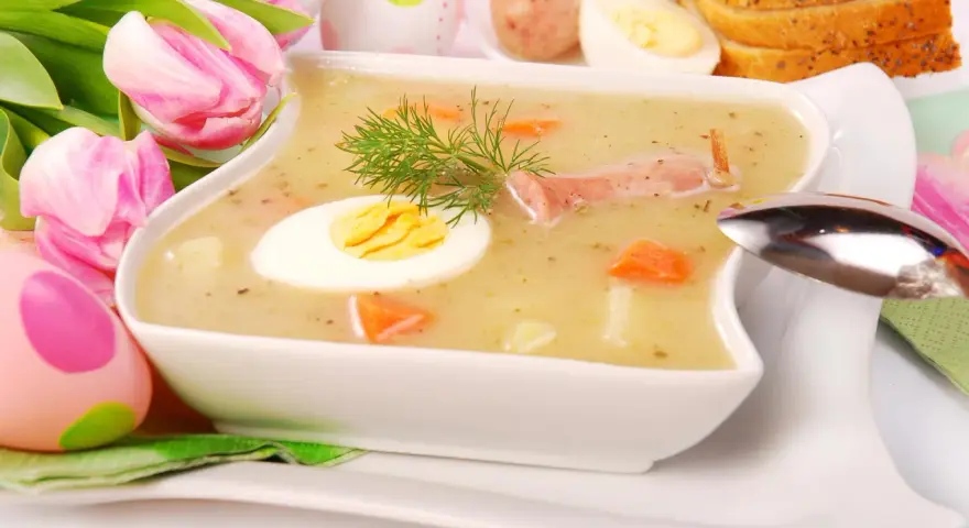 Biały barszcz z jajkiem, kiełbasą, marchewką i koprem, ozdobiony tulipanami i pisankami.