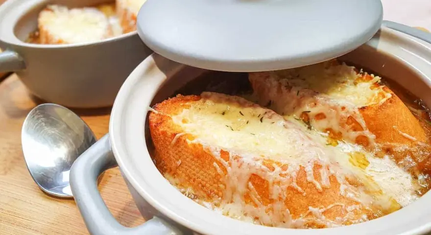 Gorąca zupa cebulowa z grzankami, zapieczona pod serem. Idealna na chłodne dni.