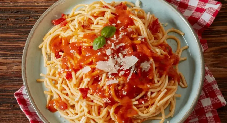 Pyszne spaghetti z sosem pomidorowym, parmezanem i listkiem bazylii. Idealne co do spaghetti na szybki obiad.