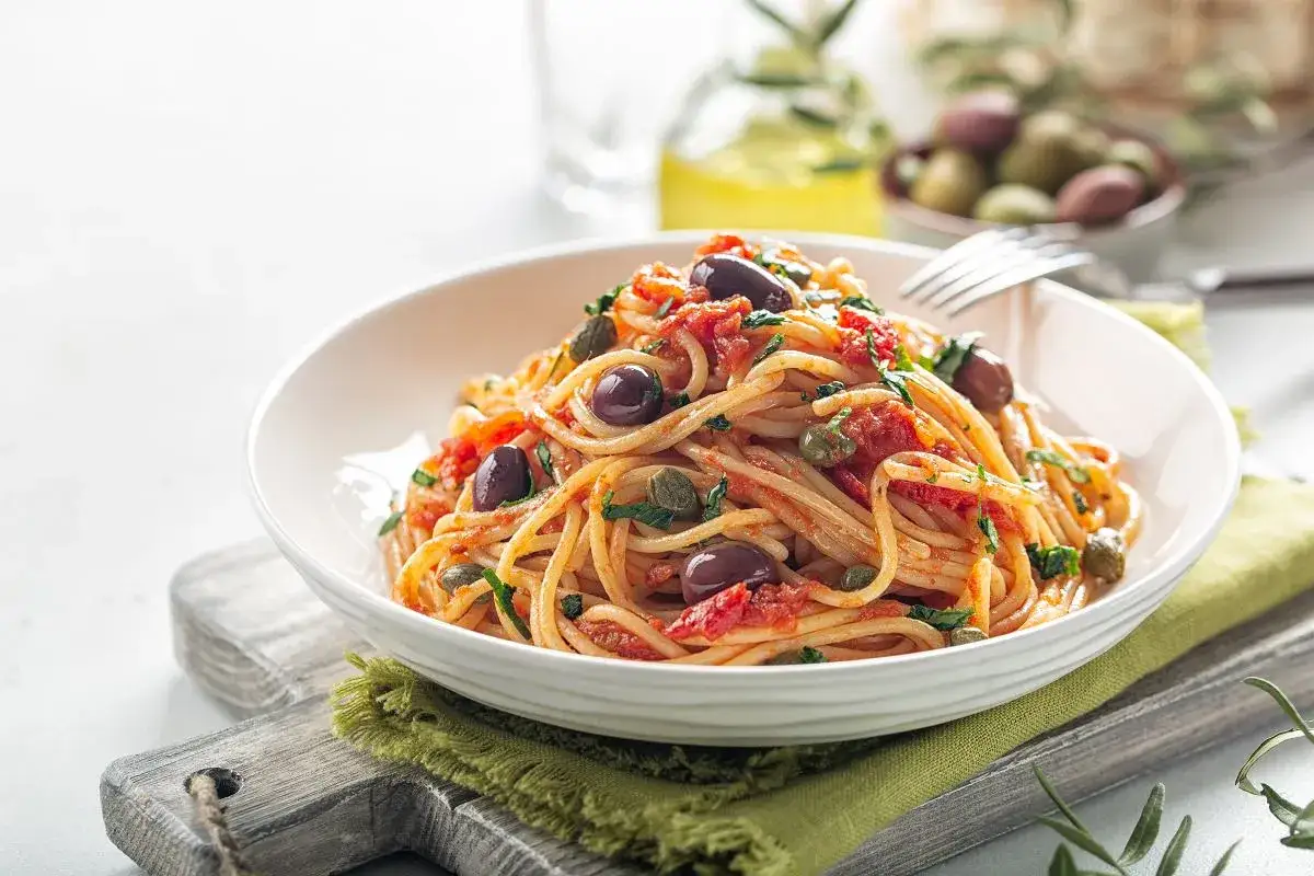 Pyszne spaghetti z pomidorami, oliwkami i kaparami. Idealne co do spaghetti na szybki obiad.