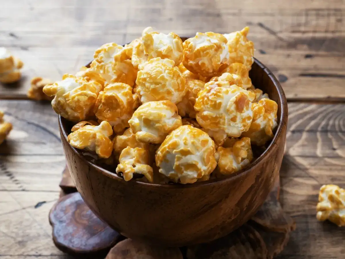 Pyszny karmelowy popcorn w drewnianej misce. Idealny na wieczór filmowy, łatwy do zrobienia w garnku.