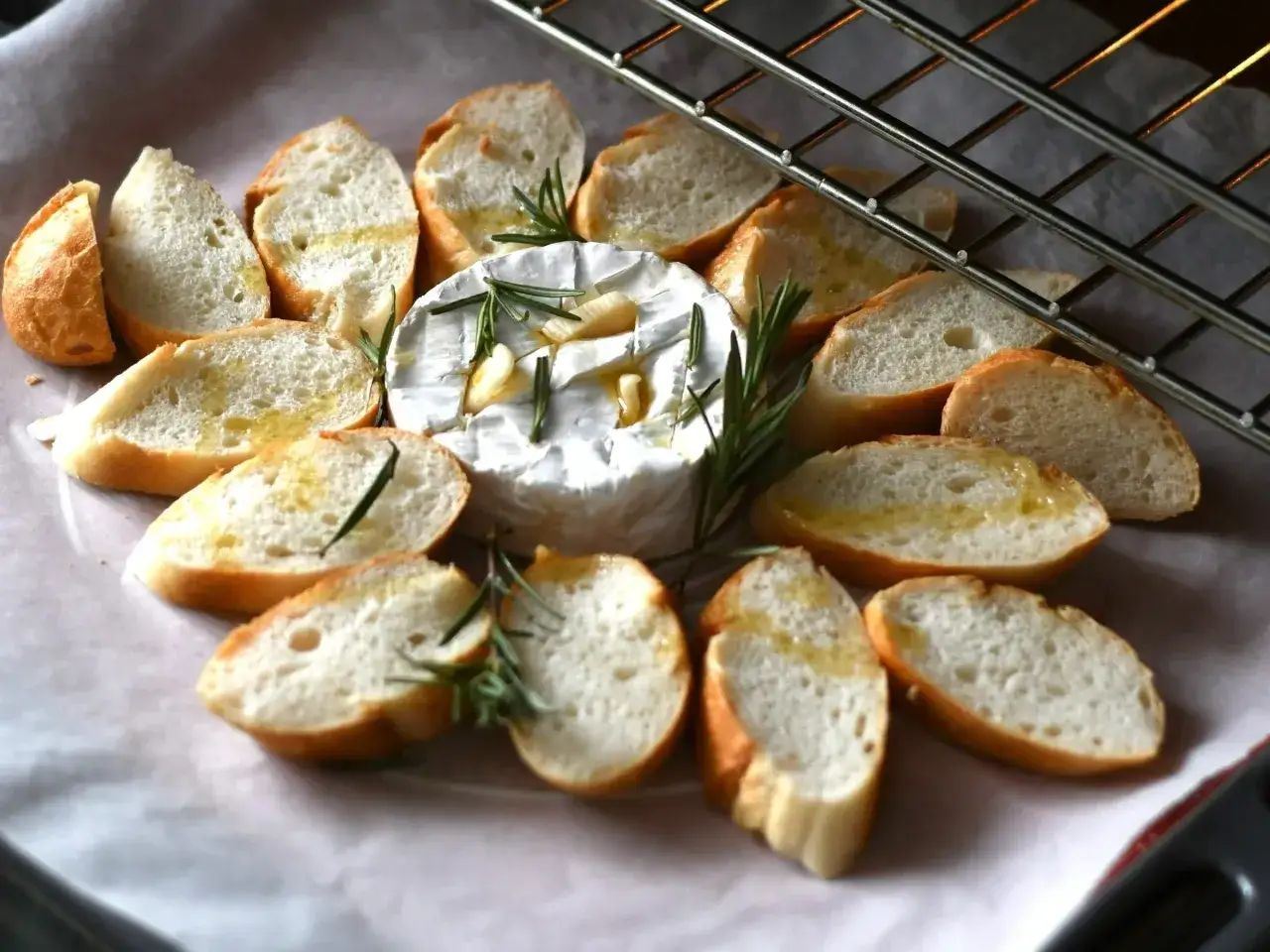 Pyszny camembert z piekarnika, otoczony chrupiącymi grzankami z rozmarynem i czosnkiem, czeka na podanie.