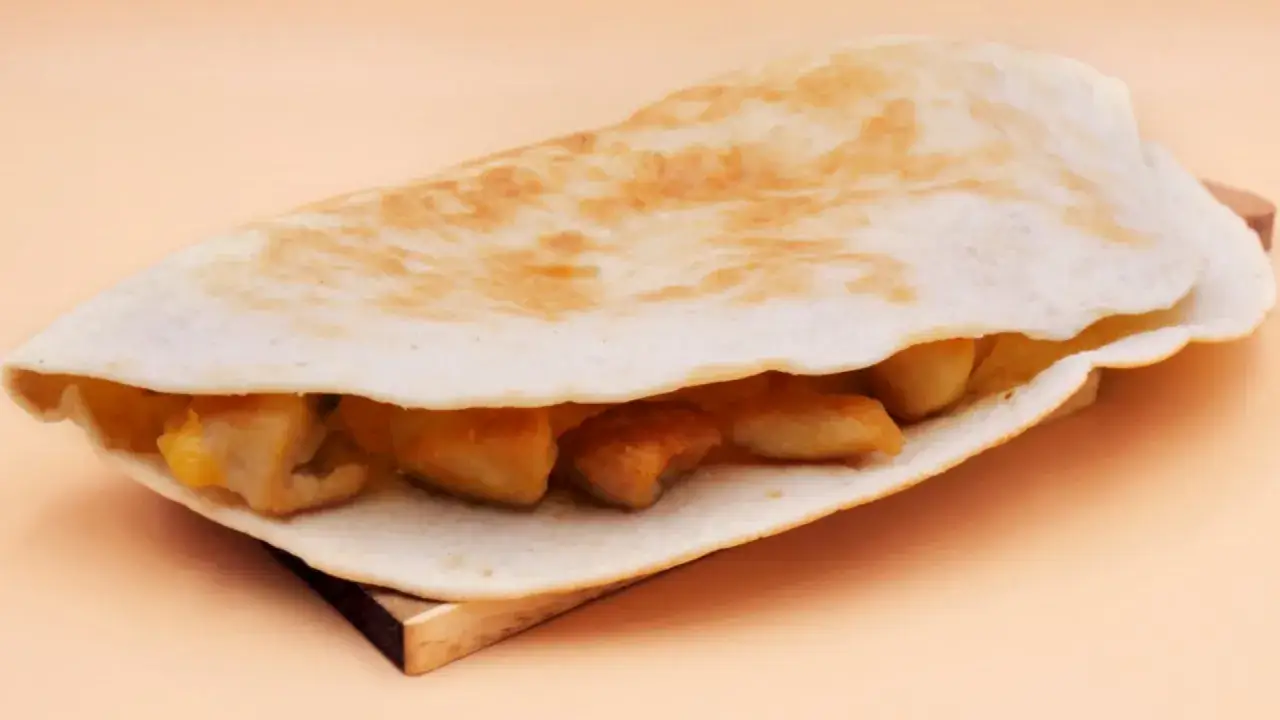 Pyszna tortilla na ciepło z patelni, wypełniona kawałkami kurczaka i ciągnącym się serem. Idealna na szybki posiłek.