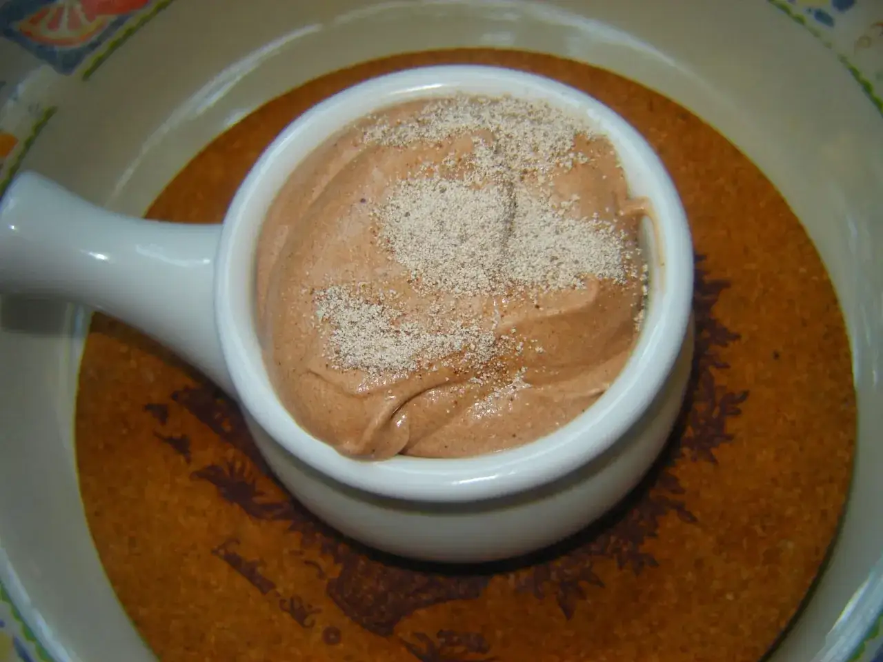 Puszysty krem cappuccino, idealny do tortu, w białej filiżance, posypany cynamonem.