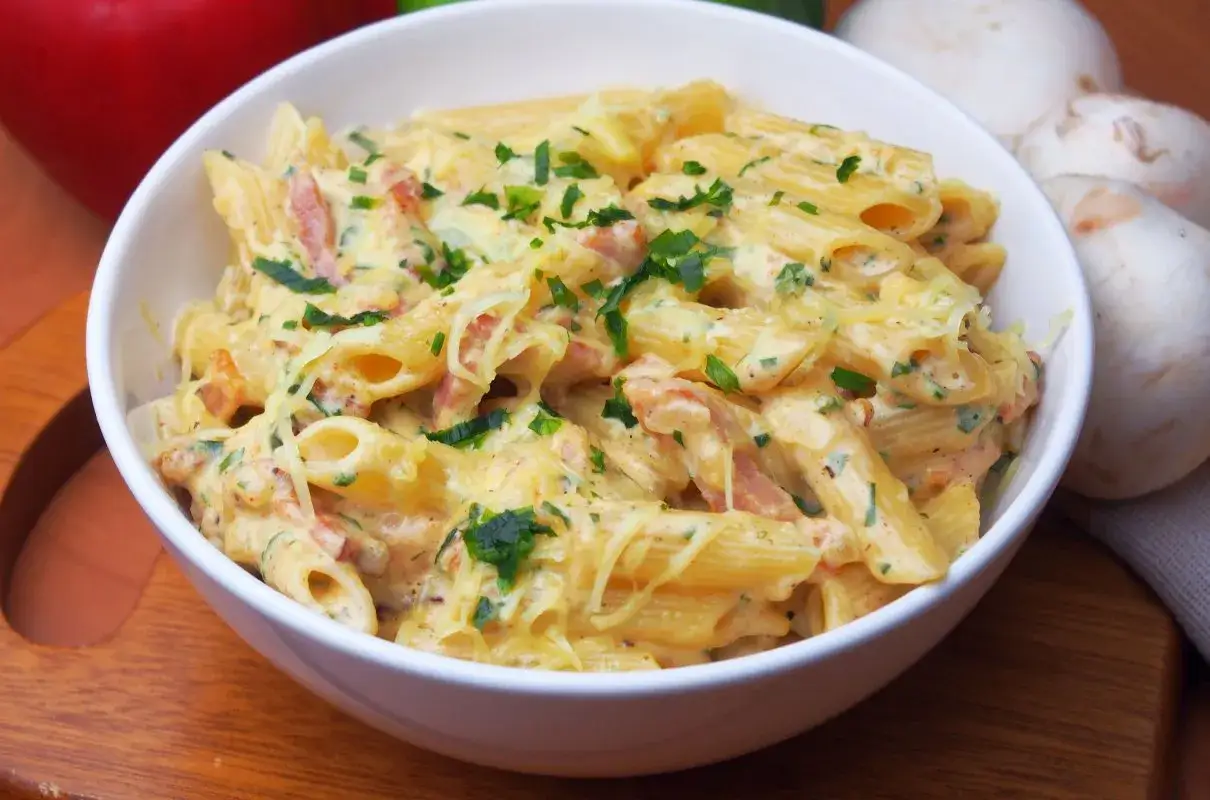 Pyszny makaron z boczkiem w kremowym sosie, posypany natką pietruszki i startym parmezanem. Idealny na szybki obiad.