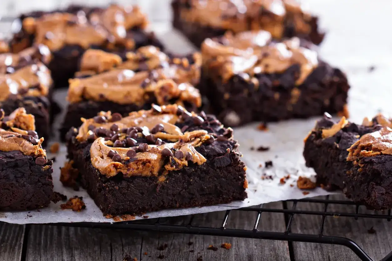Pyszne brownie z masłem orzechowym i posypką z czekoladowych dropsów, ułożone na kratce.
