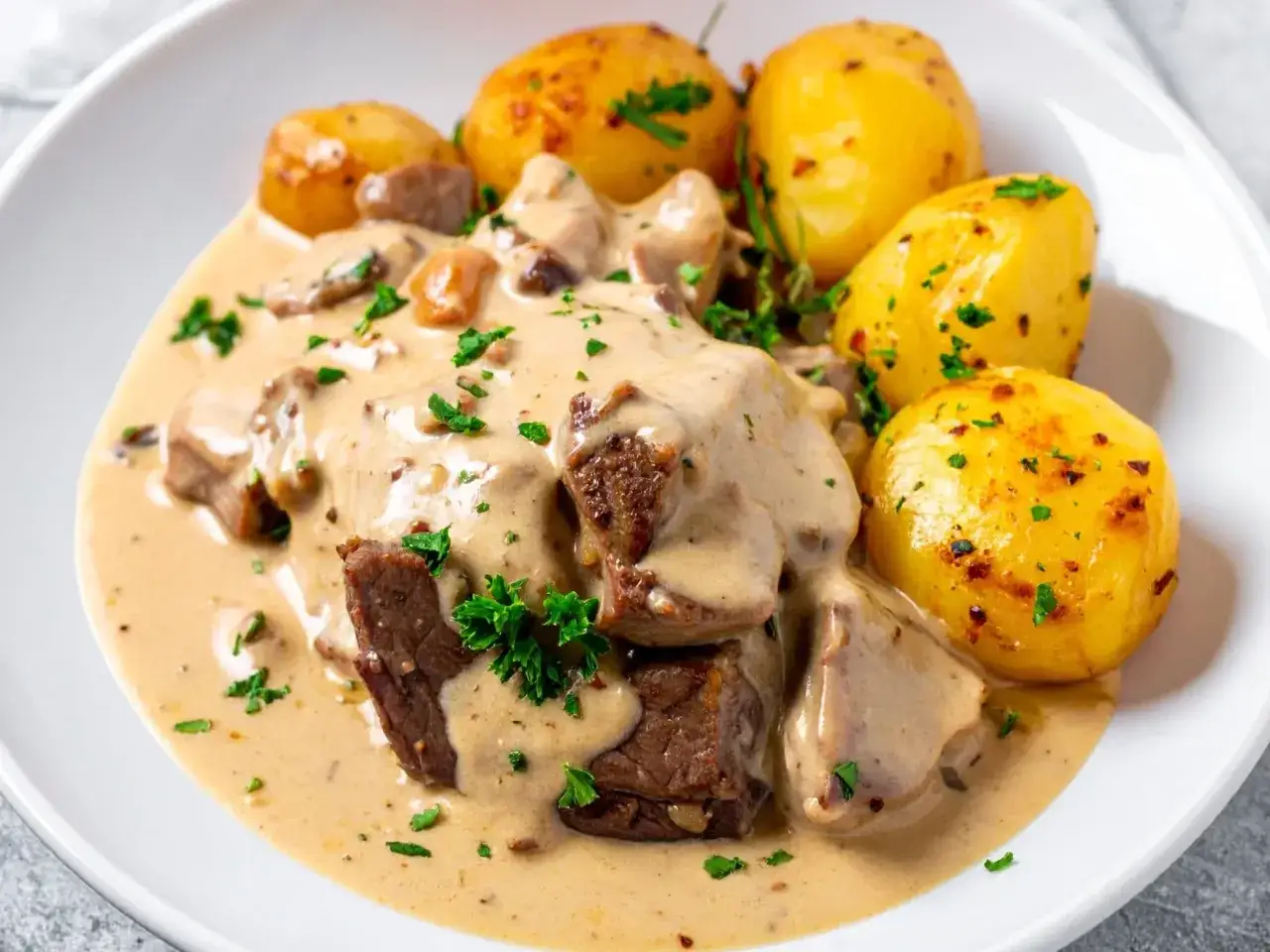 Jak zrobić sos z mięsa smażonego? Aromatyczne kawałki mięsa w kremowym sosie z pieczarkami i ziemniakami.