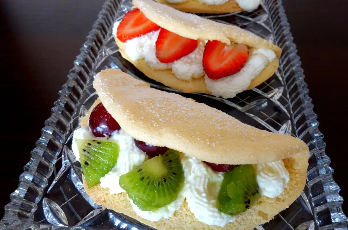 Słodki omlet z bitą śmietaną, truskawkami, kiwi i wiśniami, posypany cukrem pudrem. Pyszna przekąska na deser.