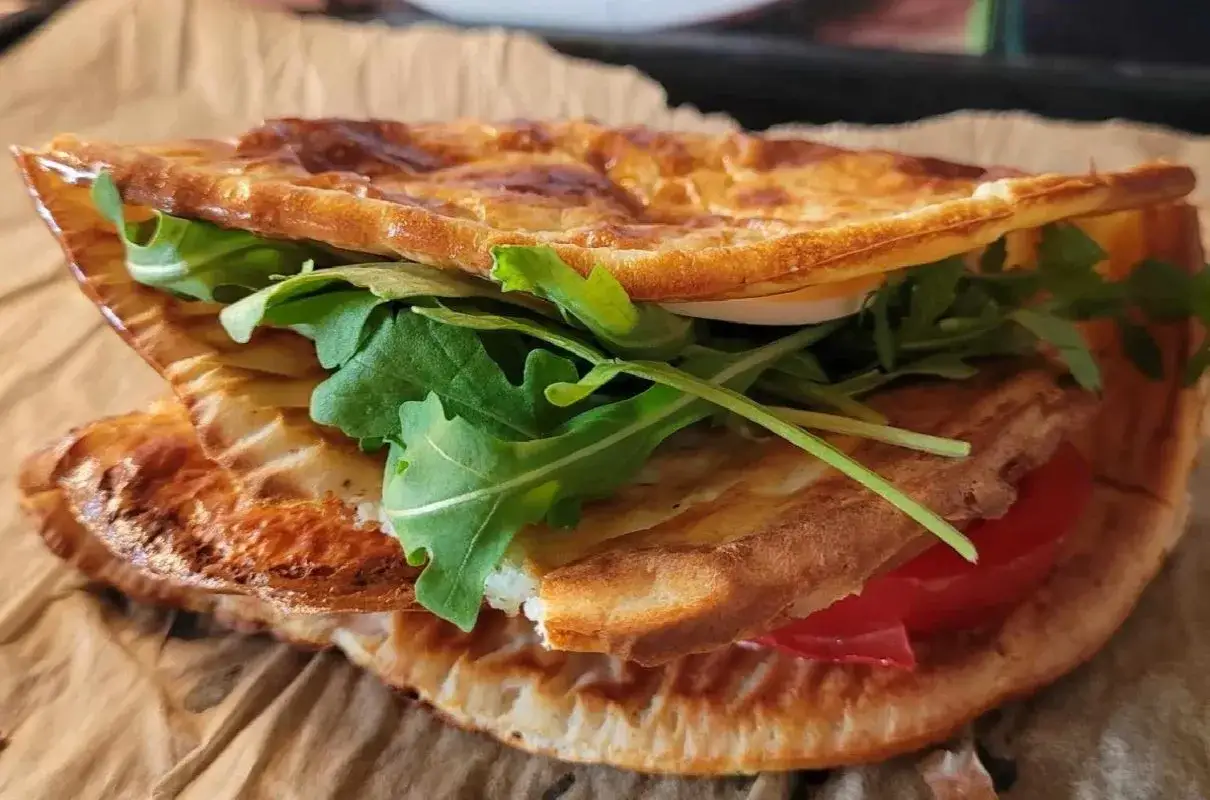 Pyszna tortilla z serka wiejskiego z rukolą i pomidorem, zapieczona na chrupko. Idealna na szybki posiłek.