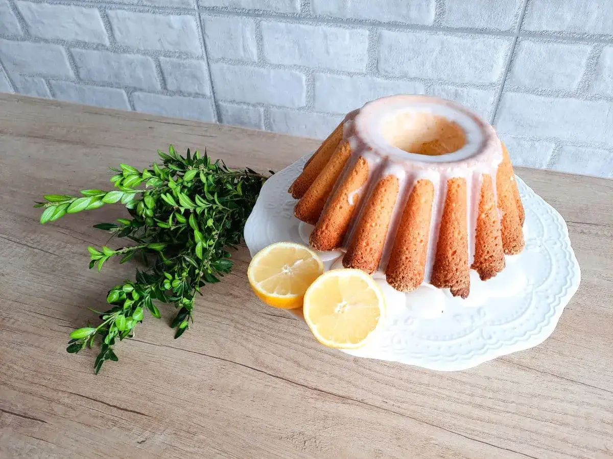 Babka majonezowa z przepisy joli, udekorowana lukrem, cytryną i gałązką bukszpanu.