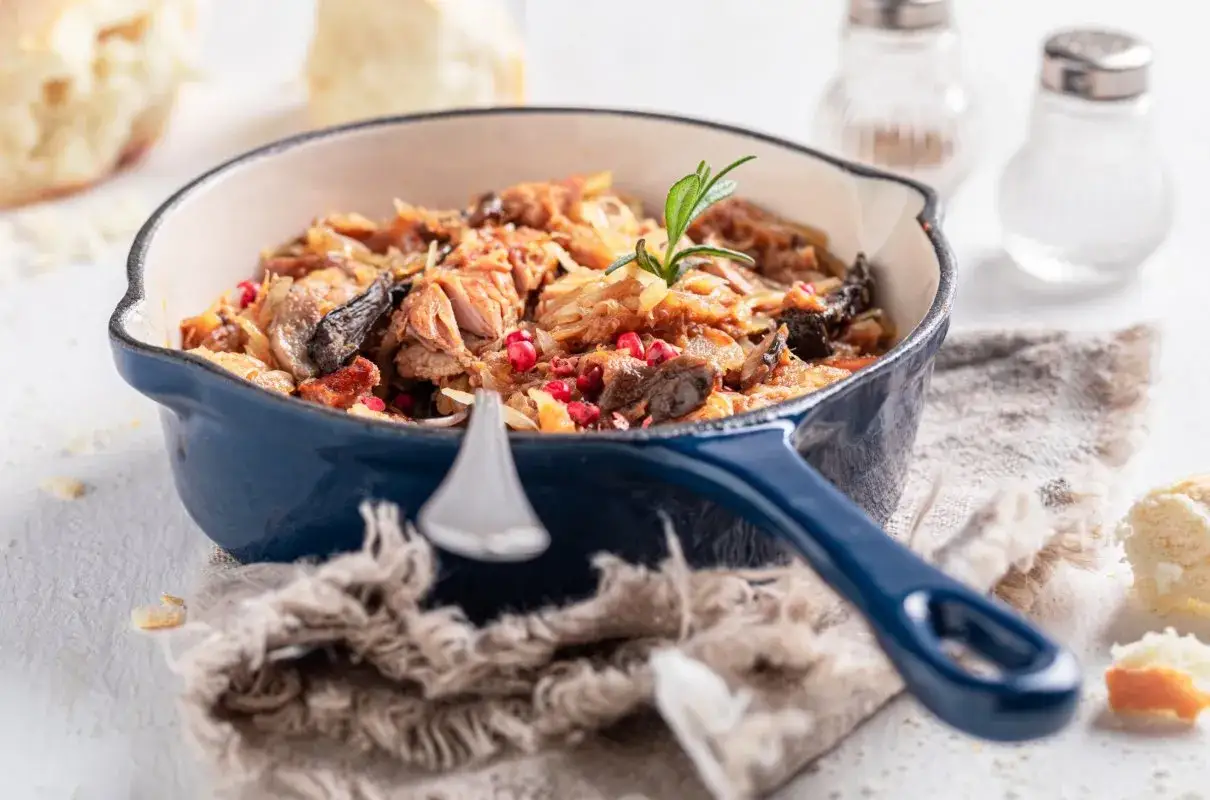 Pyszny bigos w niebieskim naczyniu, gotowy do podania. Długie gotowanie sprawia, że jest idealny.