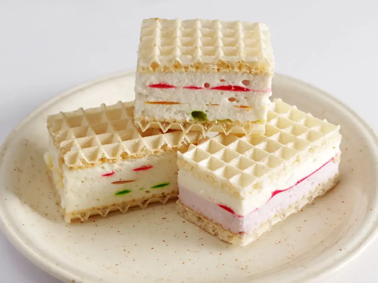 Słodkie wafle z mlekiem w proszku i kolorową galaretką, ułożone na talerzyku.