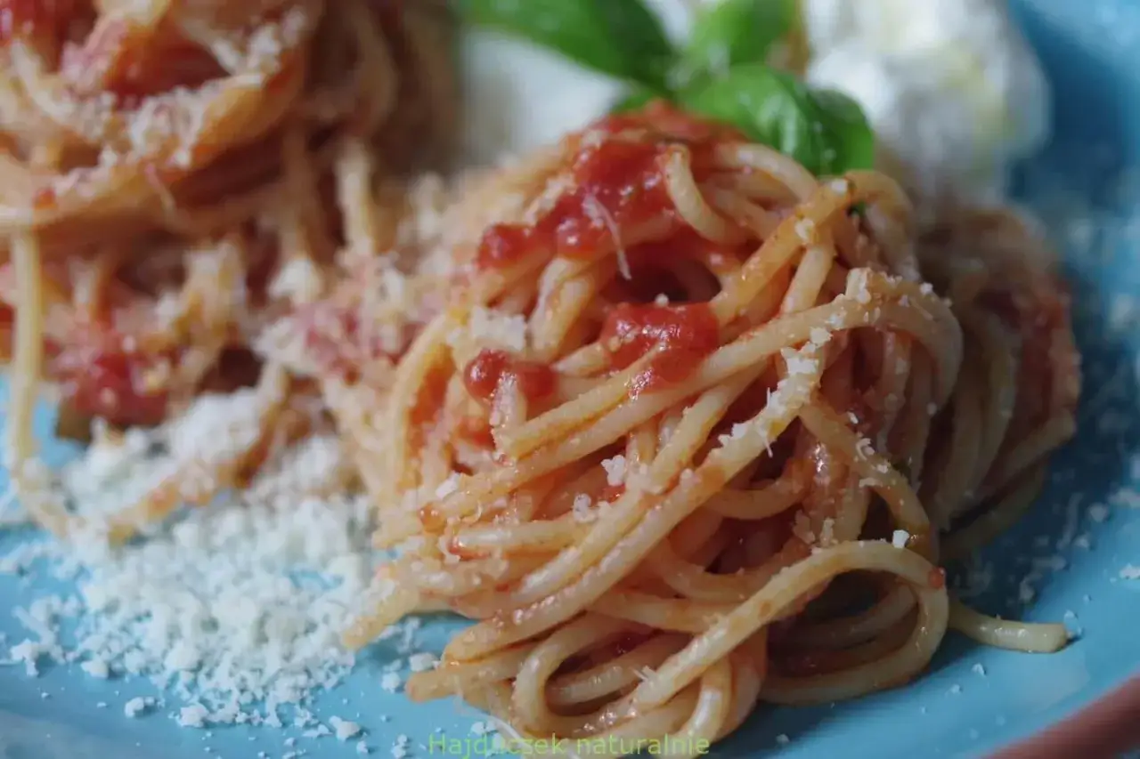 Pyszny makaron spaghetti z bogatym sosem pomidorowym, posypany parmezanem i udekorowany listkami bazylii. Idealny sos pomidorowy do makaronu.