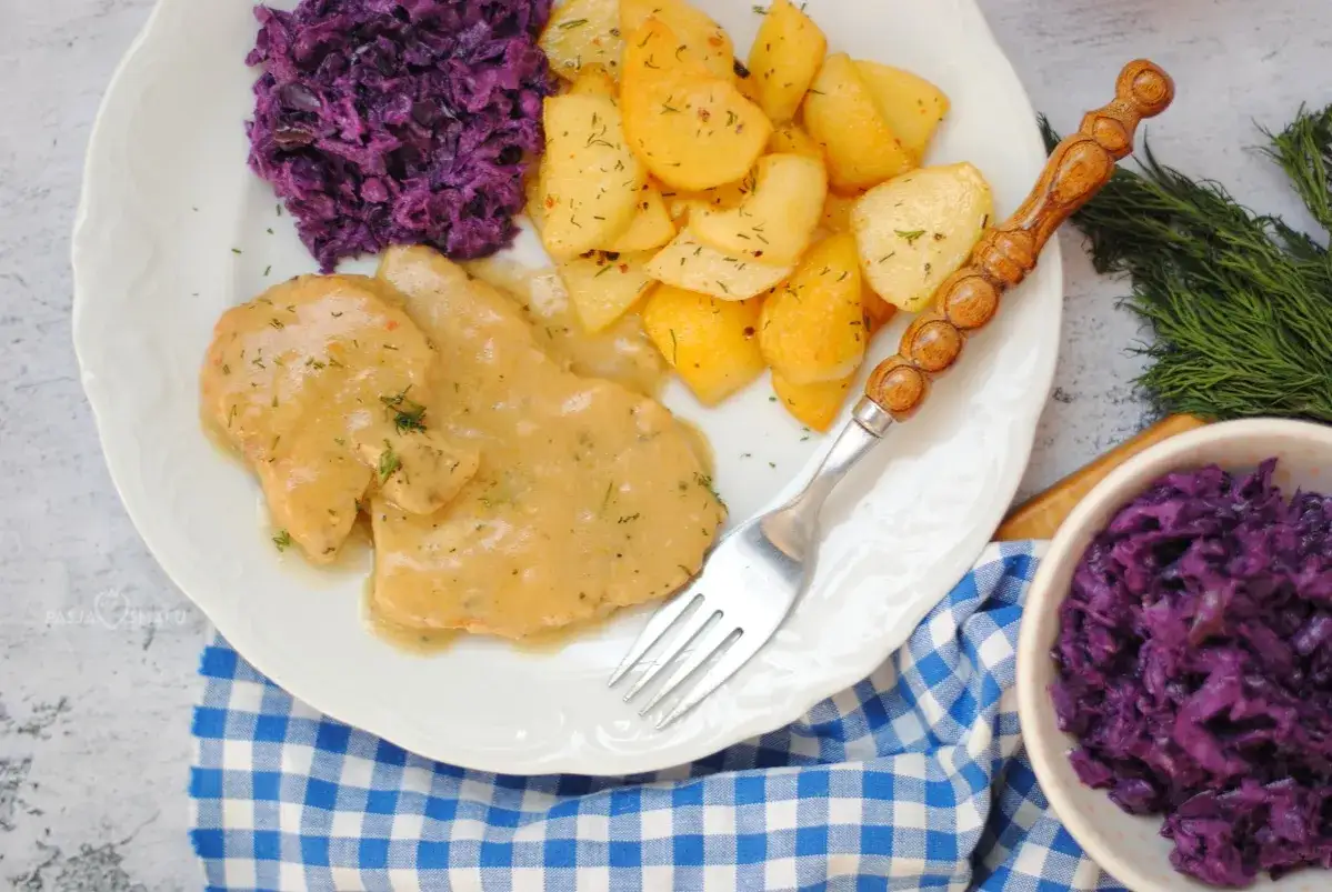 Pyszne bitki z indyka w sosie, podane z pieczonymi ziemniakami i czerwoną kapustą.