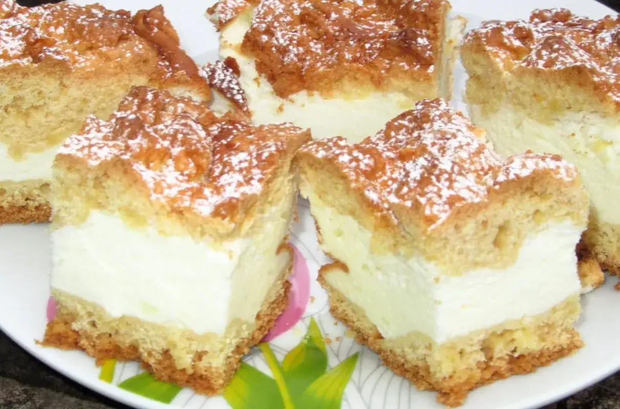 Pyszne, pieczone ciasto śmietanowiec z puszystym kremem i kruszonką, posypane cukrem pudrem. Idealne na deser.