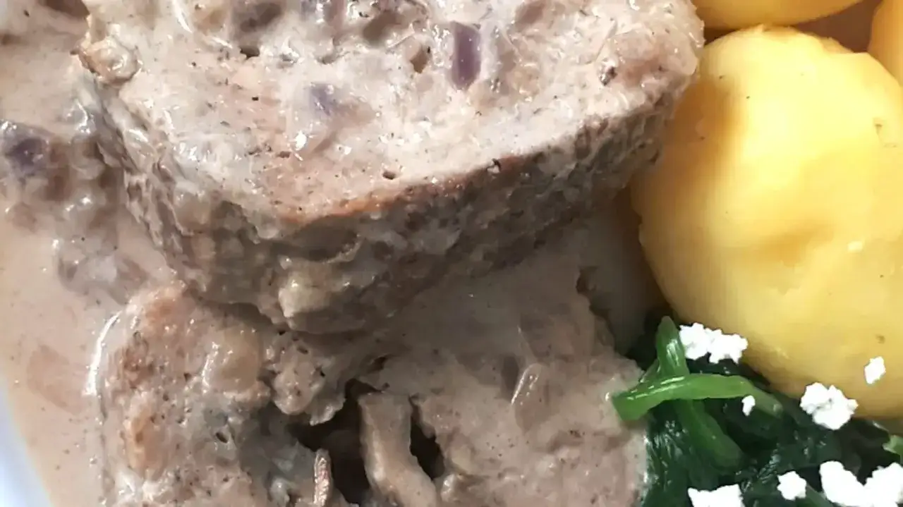 Pyszna pieczeń rzymska w kremowym sosie, podana z ziemniakami i zielonymi warzywami.