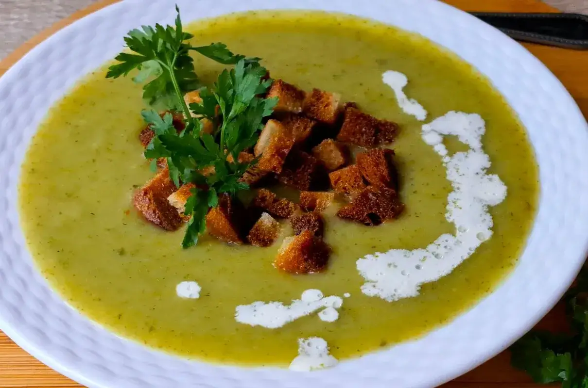 Aksamitna zupa krem z brokułów z ziemniakami, udekorowana chrupiącymi grzankami i świeżą natką pietruszki. Delikatny smak i bogactwo składników.