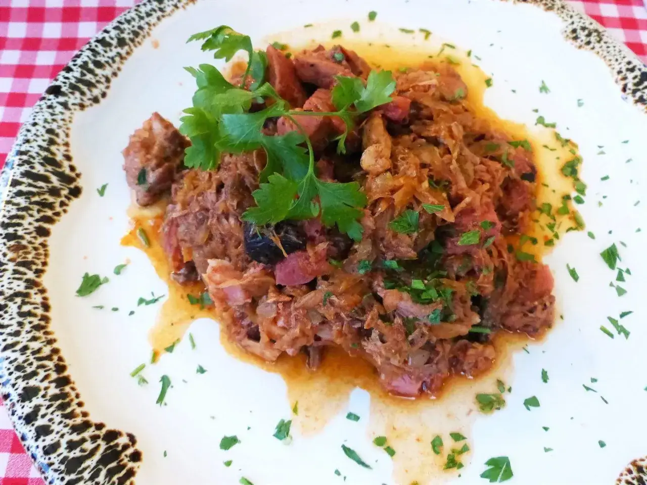 Pyszny bigos z kapusty i mięsa, udekorowany natką pietruszki. Idealny na polski obiad.