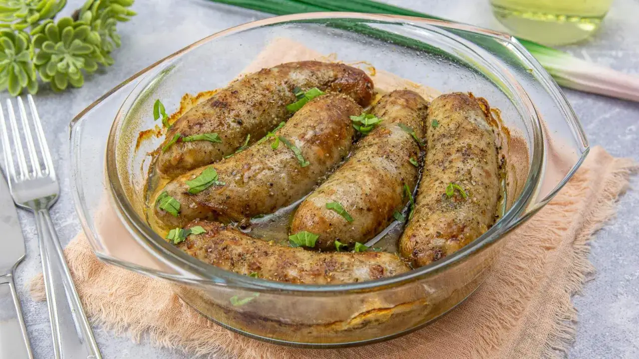 Aromatyczna biała kiełbasa pieczona w szklanym naczyniu, posypana ziołami. Idealna na obiad.